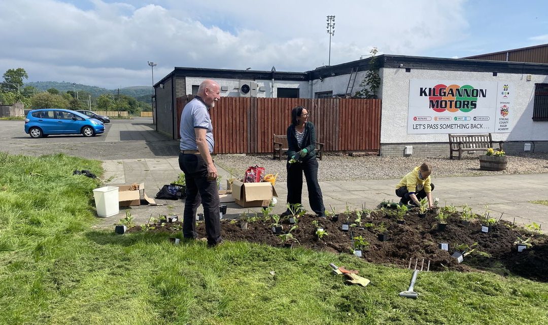Stirling rugby club volunteers gathered round bed with soil and plants